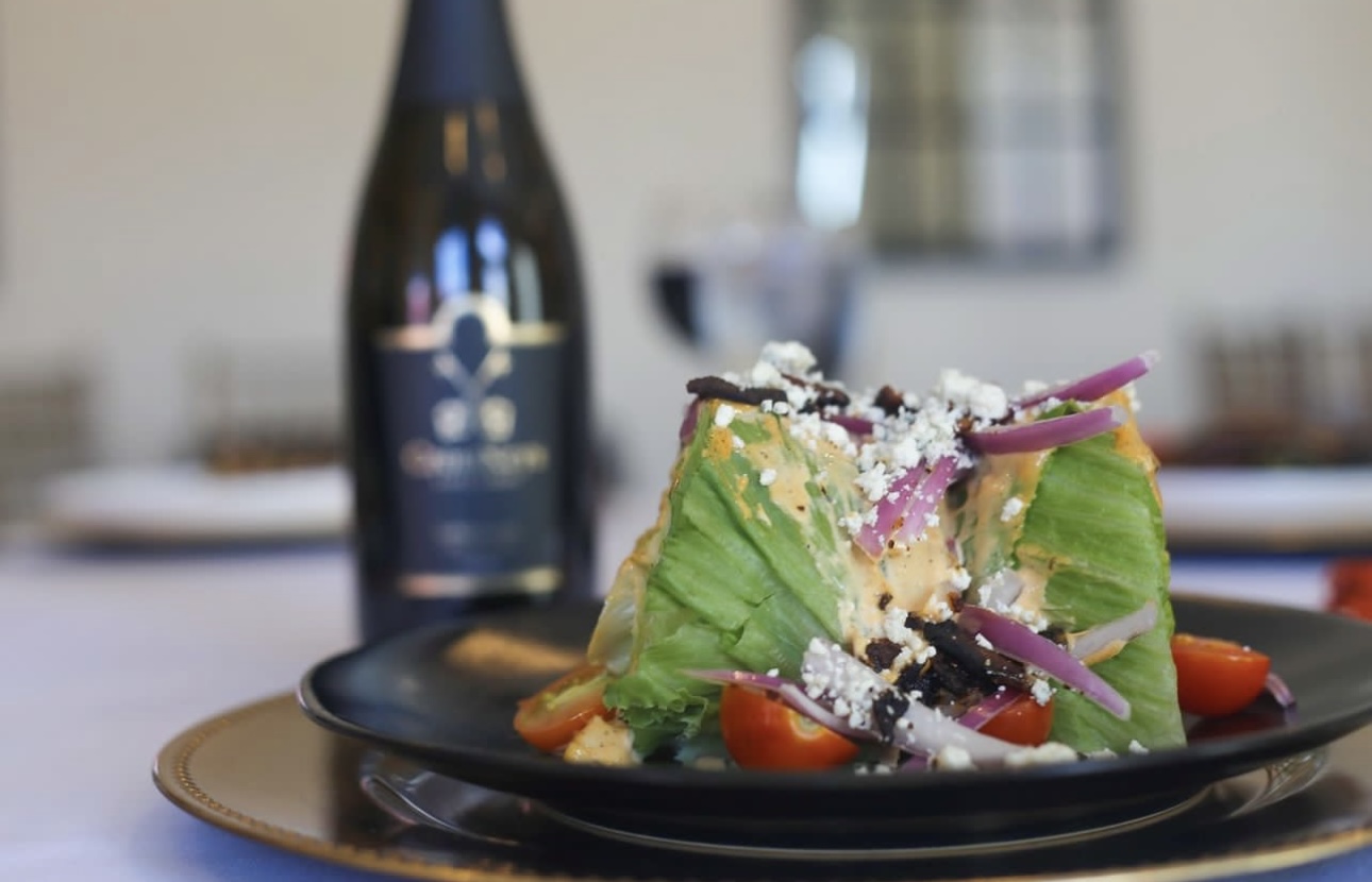 Plated salad with bottle of wine behind